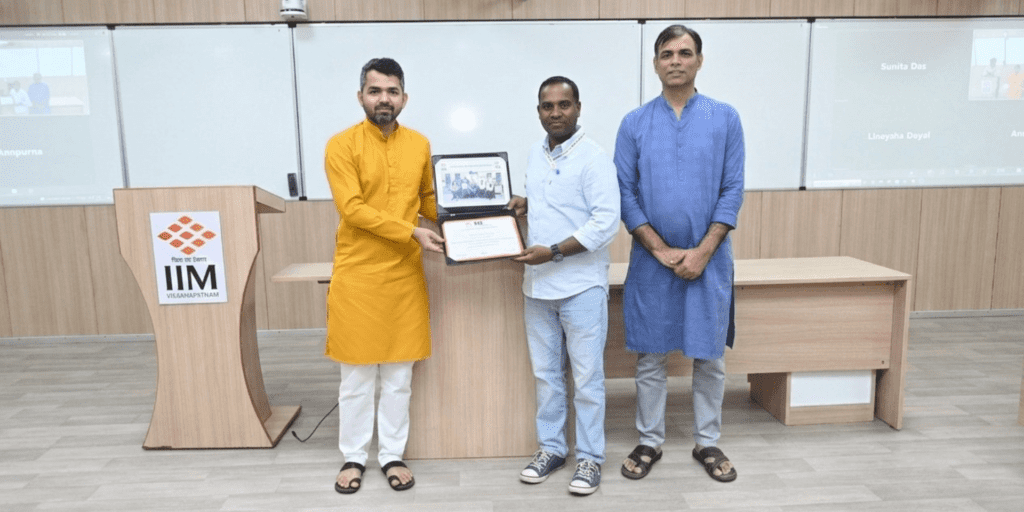 Certificate presentation ceremony at IIM Visakhapatnam with trainer receiving recognition on stage
